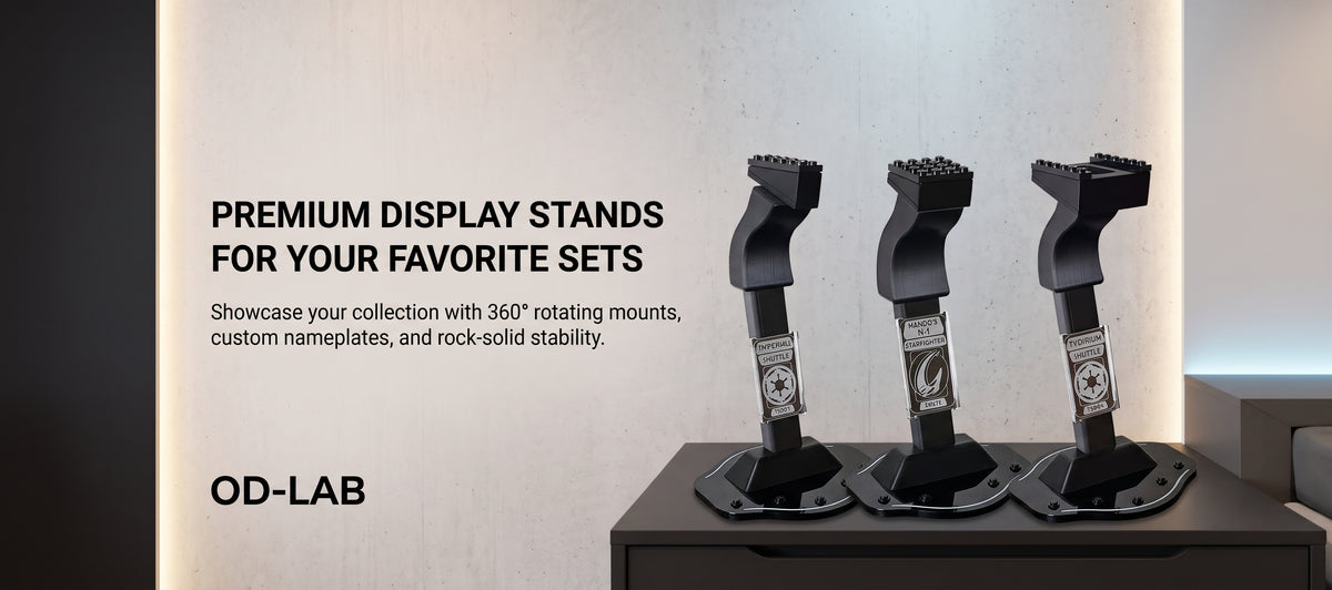 Three black OD-LAB premium display stands shown on a dark tabletop against a light wall, with promotional text on the left reading 'PREMIUM DISPLAY STANDS FOR YOUR FAVORITE SETS' and 'OD-LAB'.